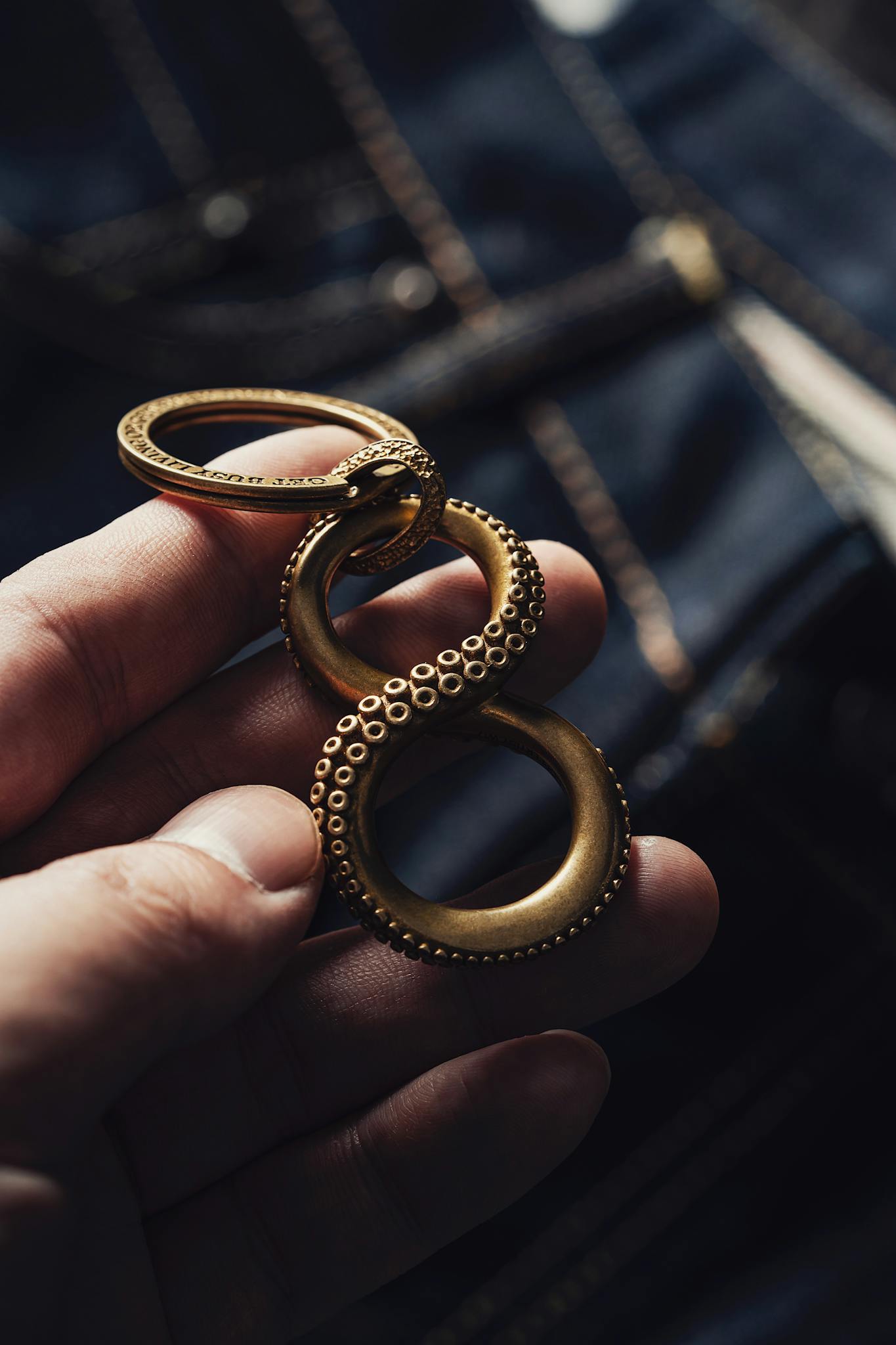 Close-up of a brass octopus keychain held in a human hand, showcasing intricate details.