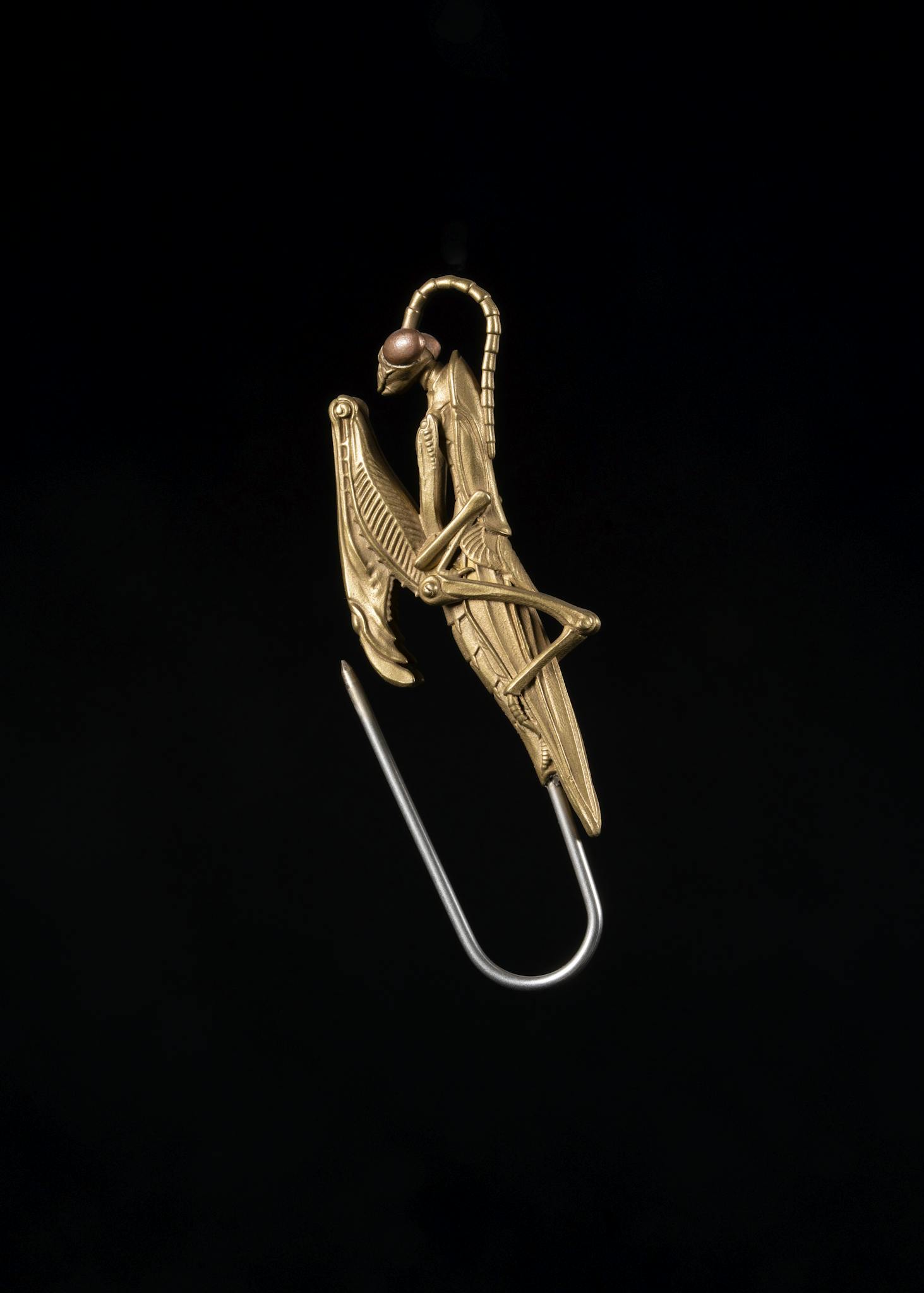 Intricate handmade mantis pin in gold on a black background, showcasing a unique artistic design.